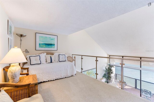 bedroom with carpet, a textured ceiling, access to outside, and vaulted ceiling