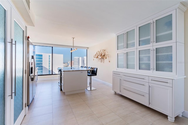 kitchen featuring a kitchen island, an inviting chandelier, white cabinetry, hanging light fixtures, and a breakfast bar area