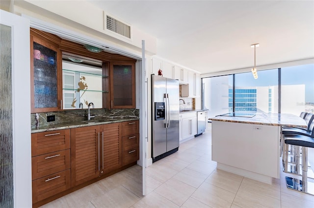 kitchen with pendant lighting, sink, a kitchen bar, white cabinetry, and stainless steel appliances