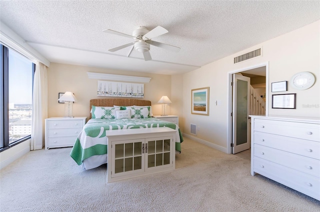 carpeted bedroom featuring a textured ceiling, multiple windows, and ceiling fan