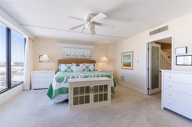 carpeted bedroom with a textured ceiling, multiple windows, and ceiling fan