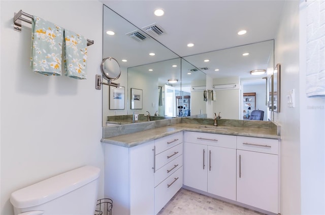 bathroom featuring an AC wall unit, vanity, and toilet