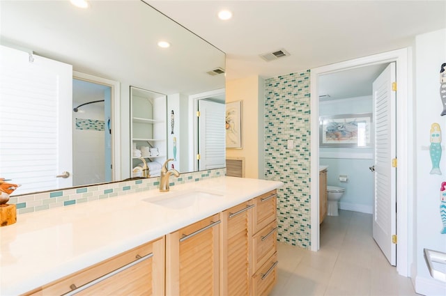 bathroom featuring tile patterned flooring, vanity, toilet, and decorative backsplash