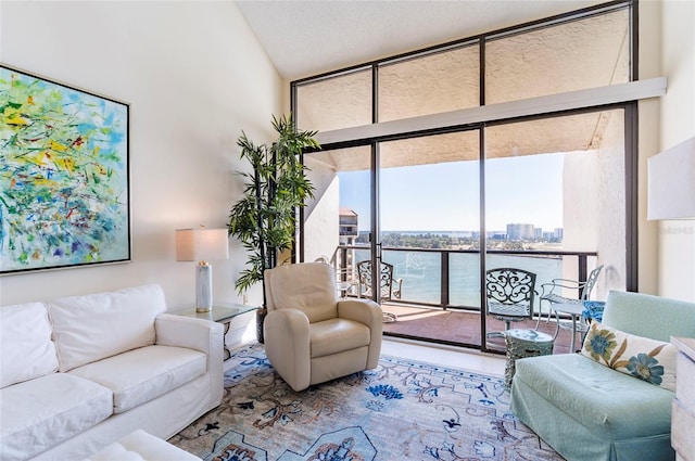 living room featuring a water view, a wall of windows, and a towering ceiling