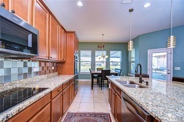 kitchen featuring sink, light stone counters, a notable chandelier, decorative light fixtures, and appliances with stainless steel finishes