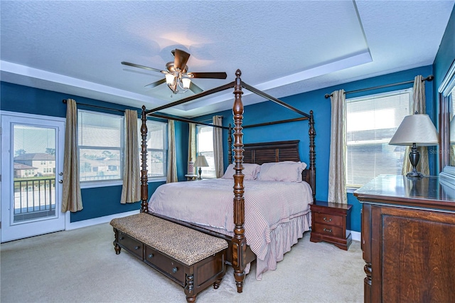 carpeted bedroom with access to exterior, a textured ceiling, a tray ceiling, and ceiling fan