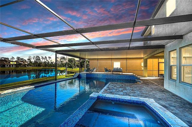 pool at dusk featuring glass enclosure, a water view, an in ground hot tub, and a patio