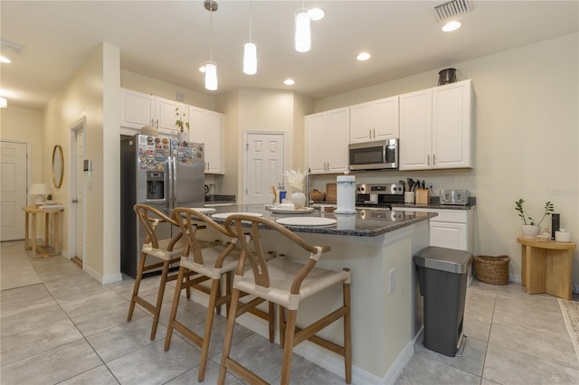 kitchen featuring light tile patterned floors, pendant lighting, a breakfast bar area, white cabinets, and appliances with stainless steel finishes