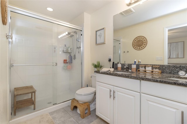 bathroom featuring tile patterned flooring, vanity, toilet, and a shower with door