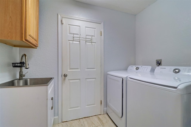 washroom featuring sink, light hardwood / wood-style flooring, cabinets, and independent washer and dryer