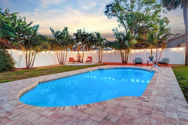 pool at dusk featuring a water view and a patio