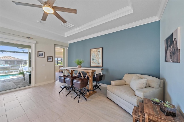 interior space with plenty of natural light, ceiling fan, a raised ceiling, and ornamental molding