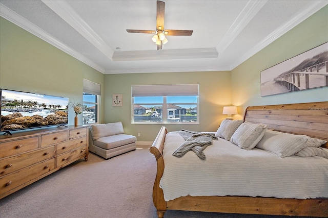 carpeted bedroom with a tray ceiling, ceiling fan, and ornamental molding