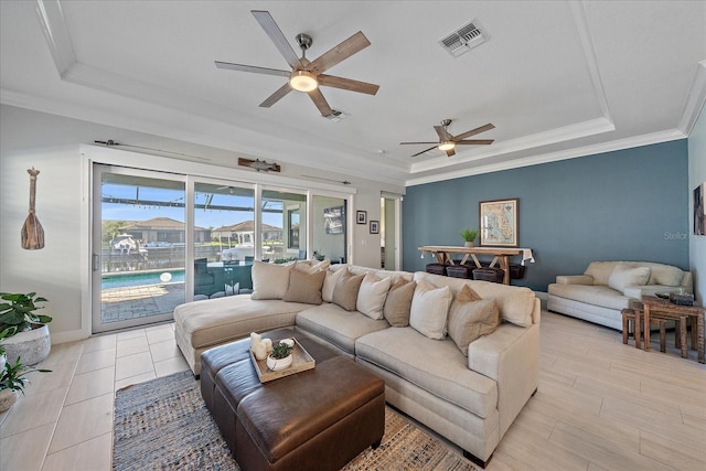 living room with a raised ceiling, ceiling fan, and crown molding