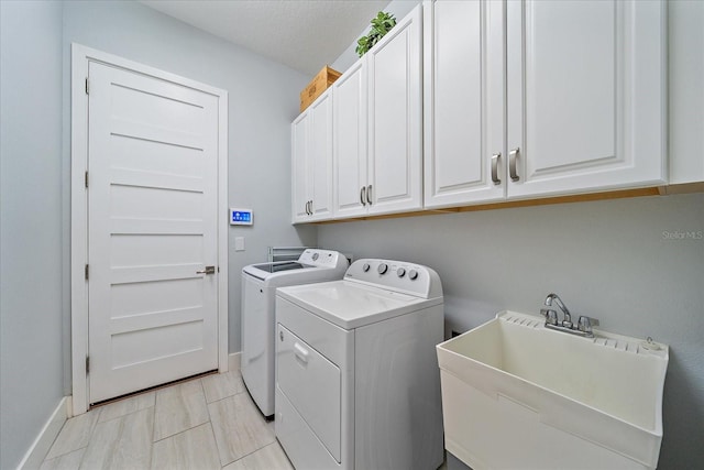 washroom with cabinets, independent washer and dryer, a textured ceiling, and sink