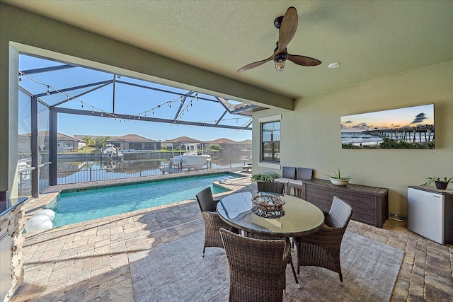 view of patio / terrace featuring a fenced in pool, glass enclosure, ceiling fan, and a water view