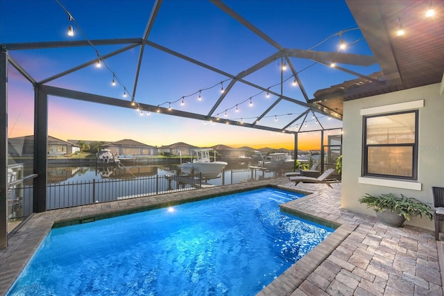 pool at dusk with a lanai, a water view, a dock, and a patio