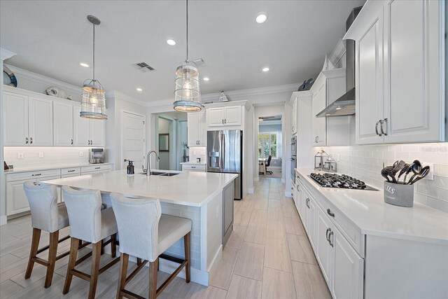 kitchen with stainless steel appliances, a sink, visible vents, an island with sink, and a kitchen bar