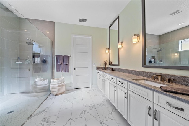 bathroom featuring marble finish floor, walk in shower, a sink, and visible vents