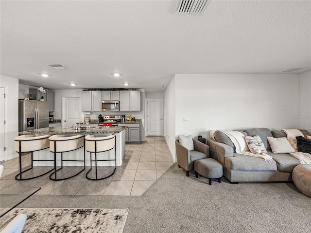 living room featuring sink, light tile patterned floors, and a textured ceiling