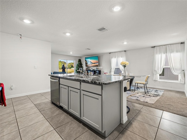 kitchen featuring sink, a textured ceiling, gray cabinets, a kitchen island with sink, and light tile patterned floors