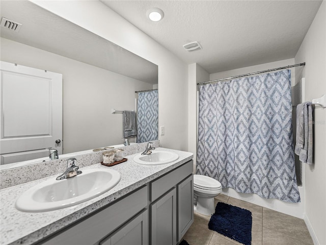 bathroom with tile patterned floors, a textured ceiling, vanity, toilet, and curtained shower