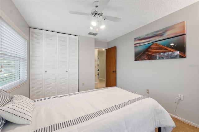 carpeted bedroom featuring a textured ceiling, ceiling fan, and a closet