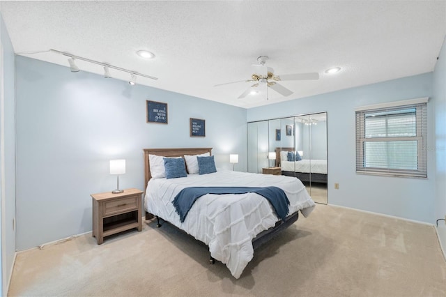 bedroom featuring ceiling fan, light carpet, track lighting, and a textured ceiling