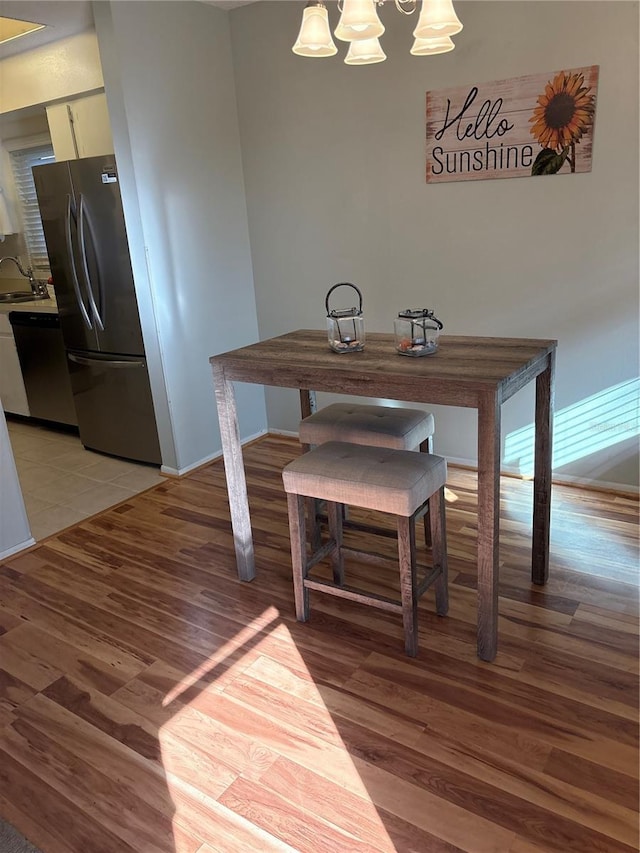 dining space with sink, a notable chandelier, and light hardwood / wood-style flooring