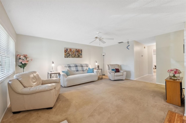 carpeted living room featuring ceiling fan and a textured ceiling