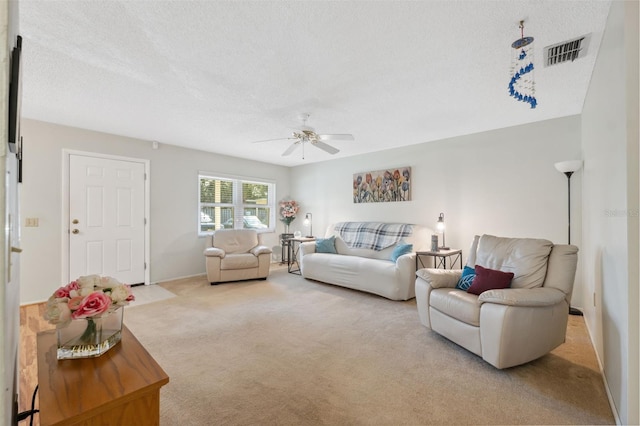 carpeted living room with ceiling fan and a textured ceiling