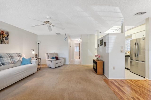 carpeted living room featuring ceiling fan and a textured ceiling