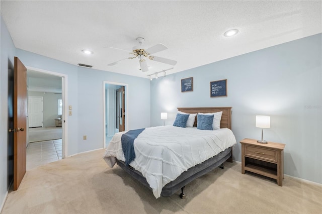 bedroom with track lighting, light carpet, a textured ceiling, and ceiling fan