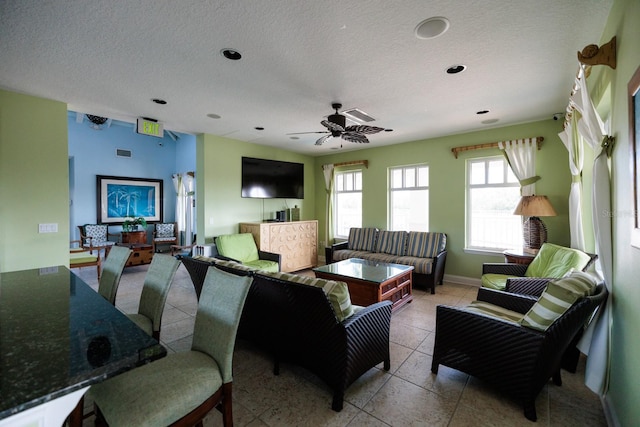 tiled living room featuring ceiling fan and a textured ceiling