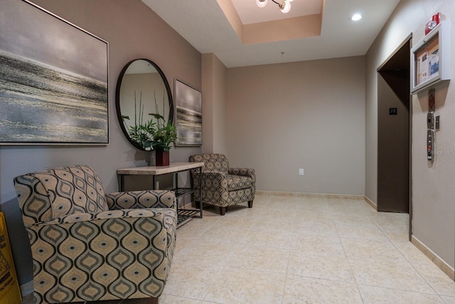 living area featuring light tile patterned floors, a tray ceiling, and a notable chandelier