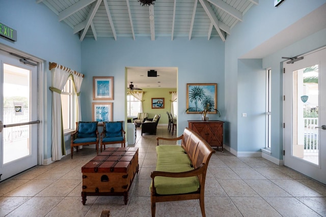 tiled living room with beam ceiling, ceiling fan, and a high ceiling