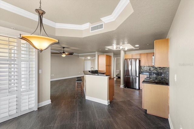 kitchen featuring stainless steel refrigerator, ceiling fan, tasteful backsplash, pendant lighting, and a tray ceiling