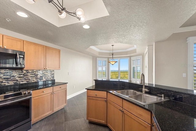 kitchen with dark stone counters, a raised ceiling, sink, hanging light fixtures, and stainless steel appliances