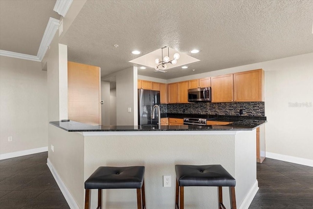 kitchen with kitchen peninsula, appliances with stainless steel finishes, and a kitchen breakfast bar