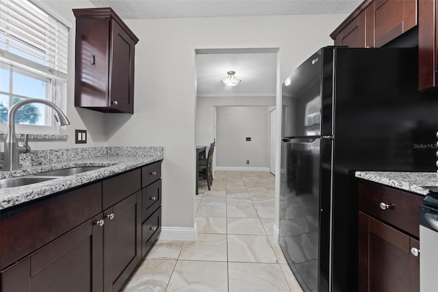 kitchen featuring black refrigerator, sink, crown molding, and a textured ceiling