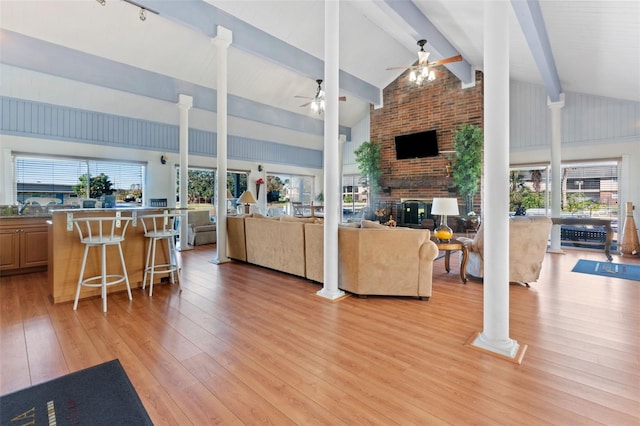 living room with beam ceiling, a fireplace, light hardwood / wood-style flooring, and high vaulted ceiling