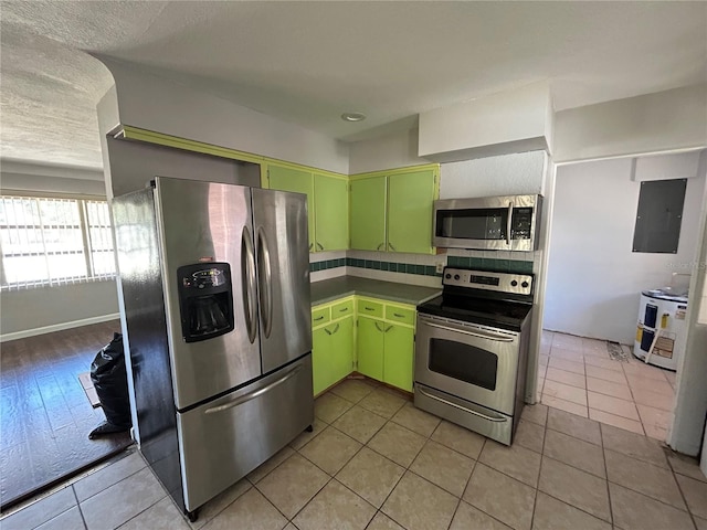 6035 Grand Blvd, New Port Richey, FL 34652 - kitchen with stainless steel appliances, backsplash, electric panel, green cabinets, and light tile patterned flooring
