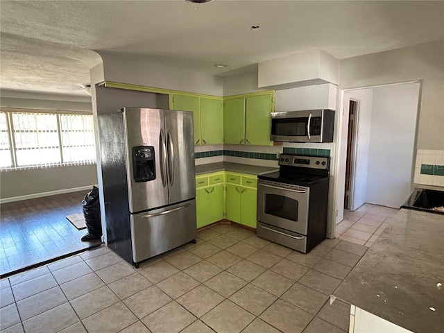 6035 Grand Blvd, New Port Richey, FL 34652 - kitchen with stainless steel appliances, green cabinetry, light tile patterned flooring, and tasteful backsplash
