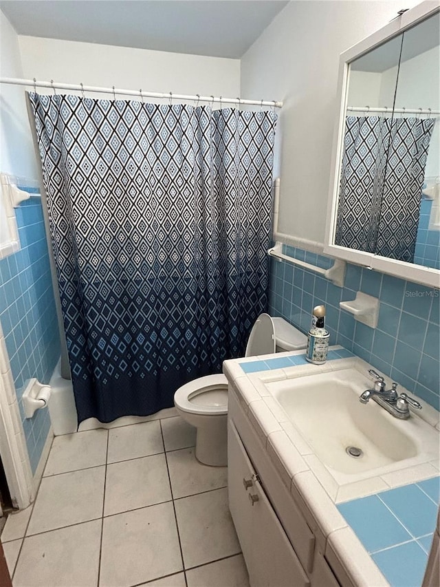 6035 Grand Blvd, New Port Richey, FL 34652 - bathroom with tile walls, toilet, vanity, tile patterned flooring, and wainscoting