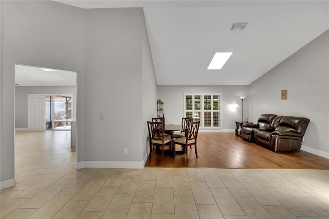 dining room featuring high vaulted ceiling, light wood-type flooring, visible vents, and baseboards