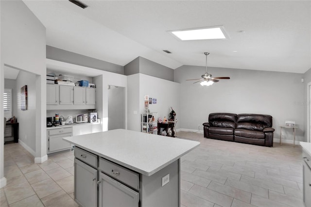 kitchen with a kitchen island, visible vents, open floor plan, light countertops, and vaulted ceiling