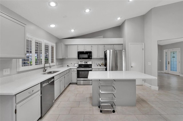 kitchen with a center island, stainless steel appliances, lofted ceiling, light countertops, and a sink