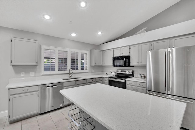 kitchen featuring lofted ceiling, recessed lighting, a breakfast bar, a sink, and appliances with stainless steel finishes