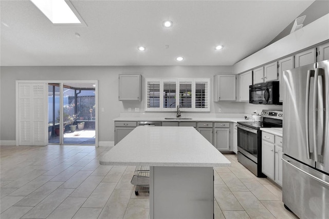 kitchen with a center island, light countertops, gray cabinetry, appliances with stainless steel finishes, and a sink