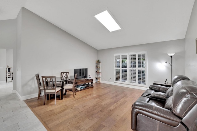 living room with high vaulted ceiling, light wood-style flooring, and baseboards